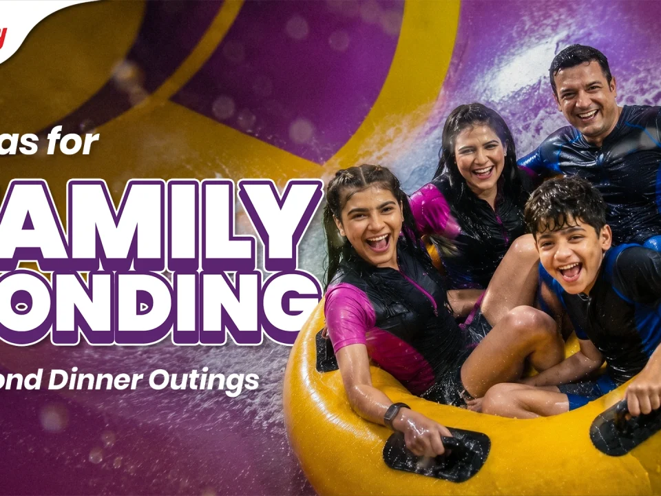 A joyful father laughing and sliding down a water slide on a yellow tube with his two excited young kids, showcasing fun father's day family activities and father's day celebration ideas near Mumbai and Pune at Wet'nJoy Lonavala.